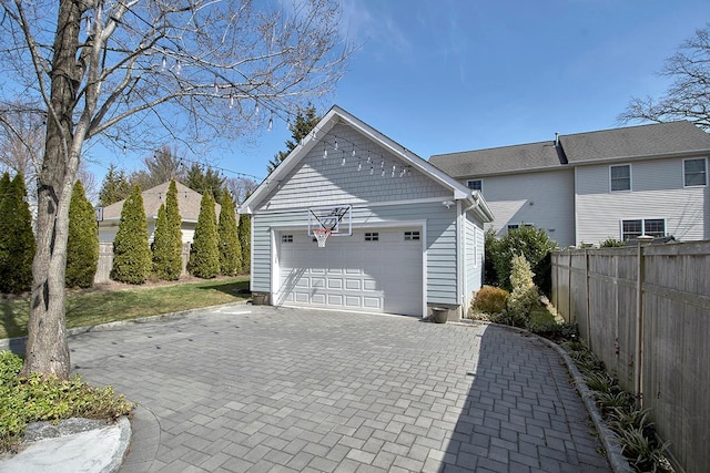 garage featuring decorative driveway and fence