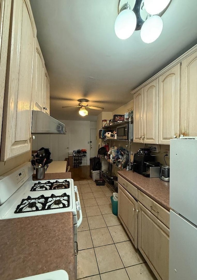 kitchen with white appliances, under cabinet range hood, light tile patterned floors, and a ceiling fan