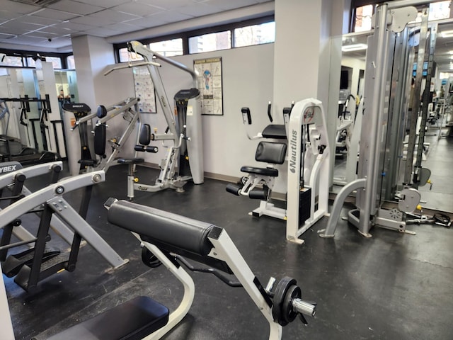 gym with baseboards and a drop ceiling