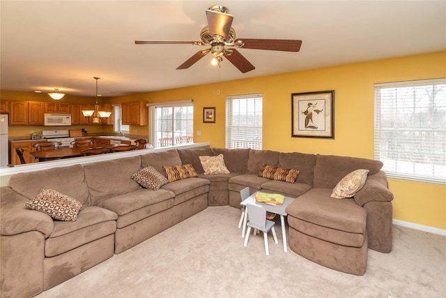 living area with light carpet, ceiling fan with notable chandelier, and baseboards