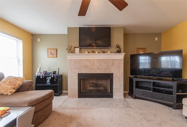 living area with a tiled fireplace, ceiling fan, and carpet floors