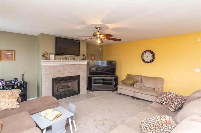 living room featuring ceiling fan, a tile fireplace, and carpet