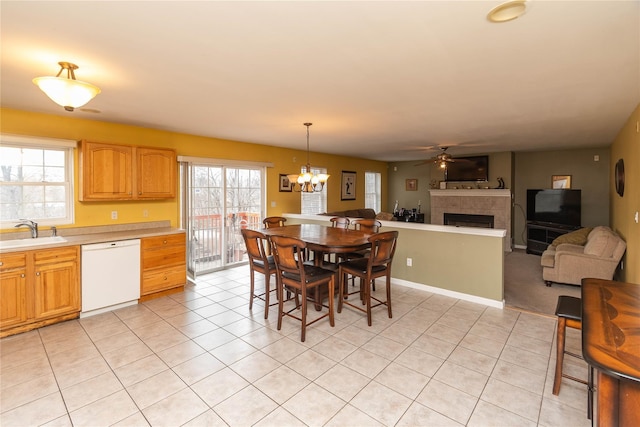 dining area with plenty of natural light, ceiling fan with notable chandelier, light tile patterned floors, and a tile fireplace