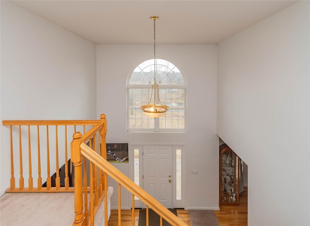 staircase with a notable chandelier, wood finished floors, and a towering ceiling