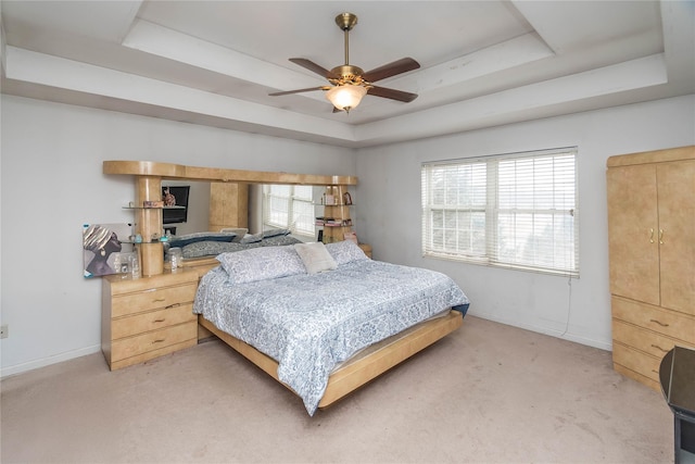 bedroom with light carpet, ceiling fan, baseboards, and a tray ceiling