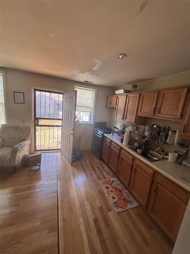 kitchen with light countertops, a sink, light wood-style flooring, and brown cabinets