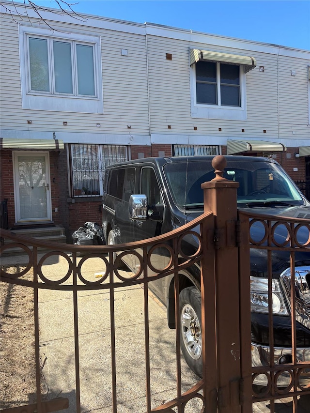 view of property featuring entry steps, brick siding, and fence