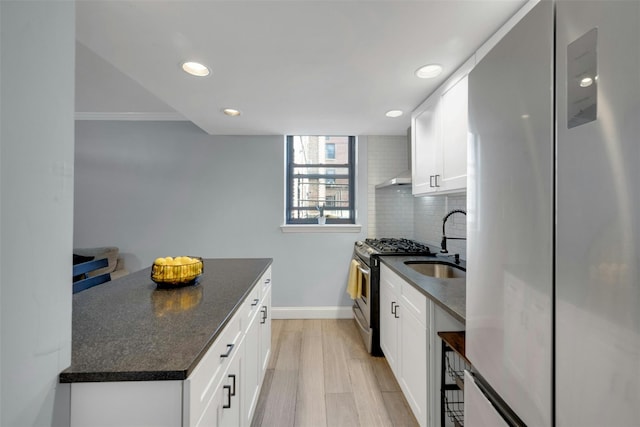 kitchen featuring light wood-style flooring, a sink, tasteful backsplash, stainless steel appliances, and white cabinets