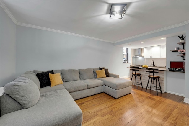 living room with crown molding, light wood-type flooring, and baseboards