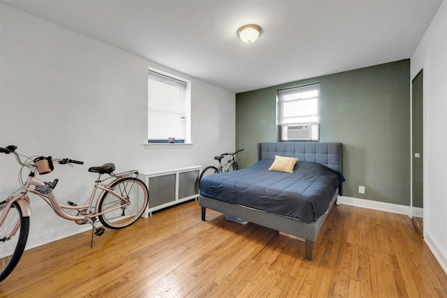 bedroom featuring cooling unit, baseboards, and light wood-style flooring