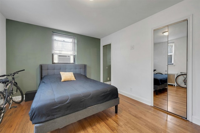 bedroom featuring cooling unit, baseboards, and light wood finished floors