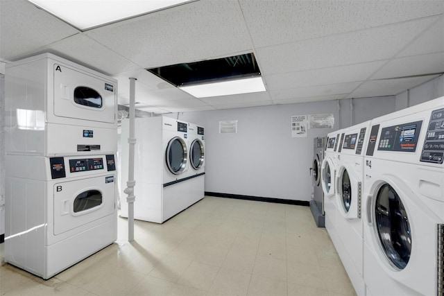 shared laundry area featuring washing machine and clothes dryer, light floors, stacked washer / drying machine, and baseboards