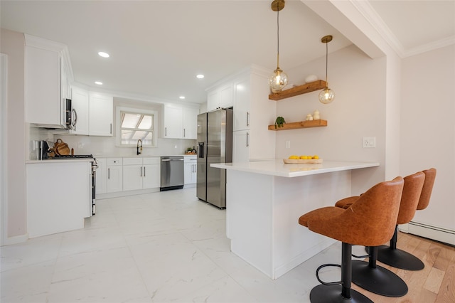 kitchen featuring a peninsula, a sink, ornamental molding, stainless steel appliances, and a kitchen breakfast bar