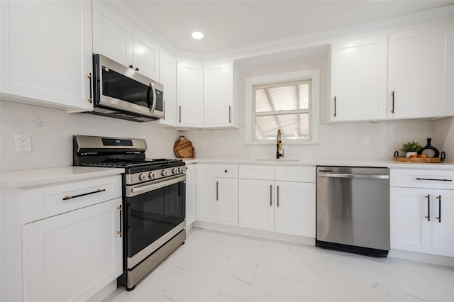 kitchen with marble finish floor, a sink, white cabinetry, stainless steel appliances, and light countertops