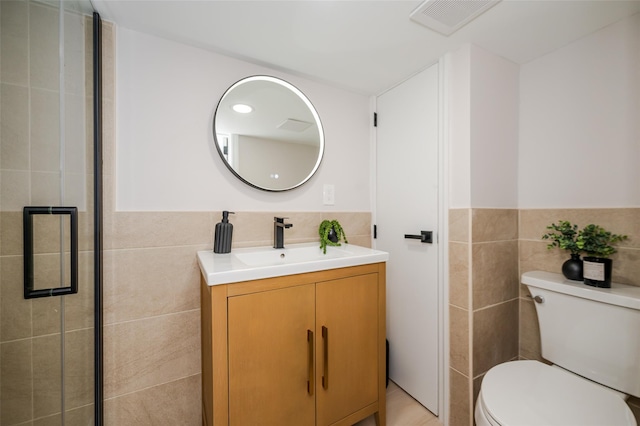 bathroom with toilet, tile walls, and vanity