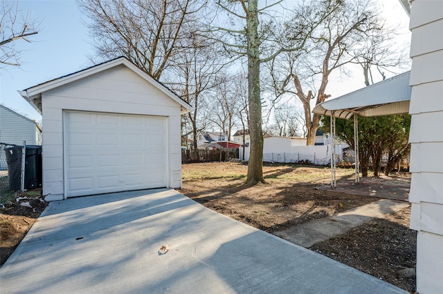 view of yard featuring concrete driveway, a detached garage, an outdoor structure, and fence