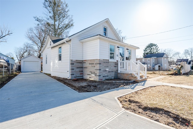 view of front of house featuring stone siding, concrete driveway, a detached garage, and an outdoor structure