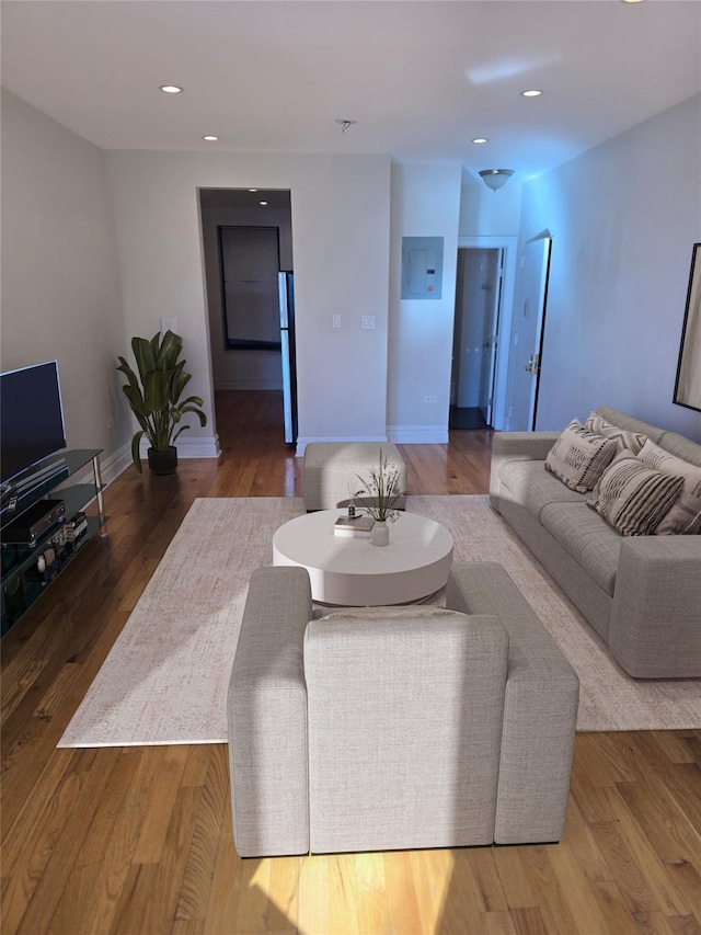 living area featuring electric panel, recessed lighting, wood finished floors, and baseboards