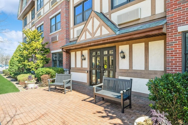 property entrance featuring stucco siding, brick siding, and french doors