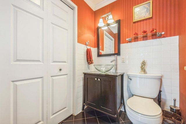 half bath featuring tile patterned flooring, wallpapered walls, a wainscoted wall, toilet, and vanity