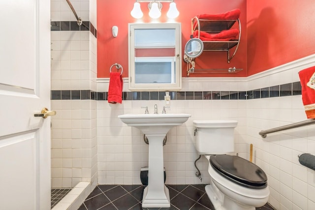 full bathroom featuring tile patterned flooring, a wainscoted wall, toilet, and tile walls