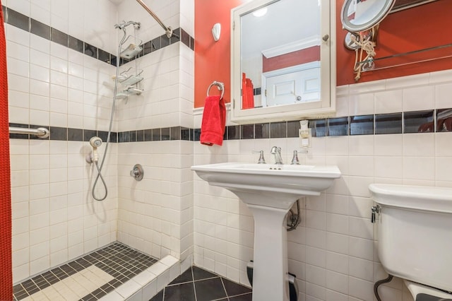 bathroom featuring toilet, a stall shower, and tile walls