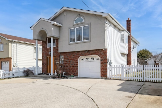 view of front of property featuring driveway, brick siding, fence, and stucco siding