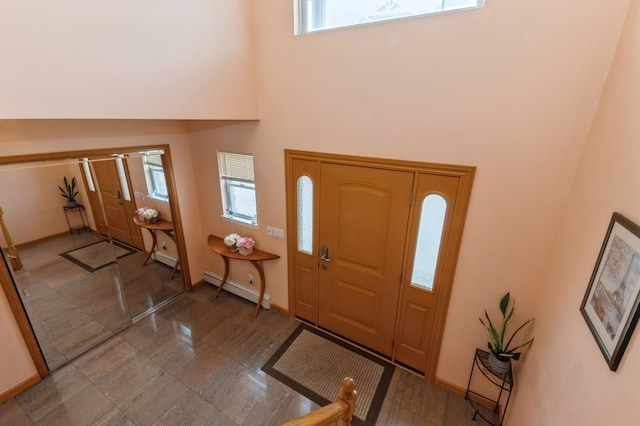 entrance foyer featuring a baseboard heating unit, a high ceiling, and baseboards