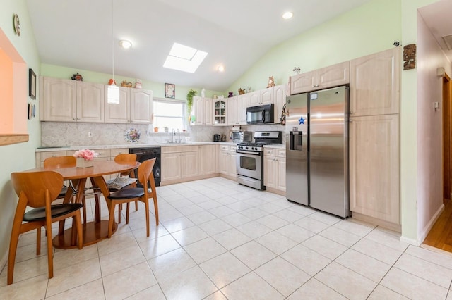 kitchen featuring tasteful backsplash, light countertops, lofted ceiling with skylight, a sink, and black appliances