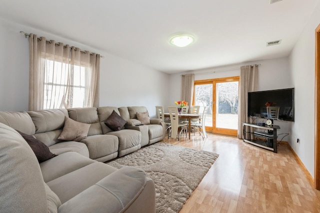 living area with visible vents and light wood-style floors