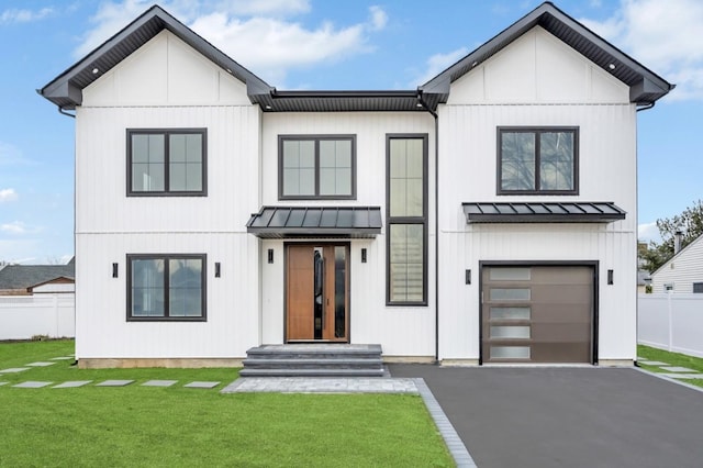 modern inspired farmhouse with a front yard, fence, a standing seam roof, a garage, and metal roof