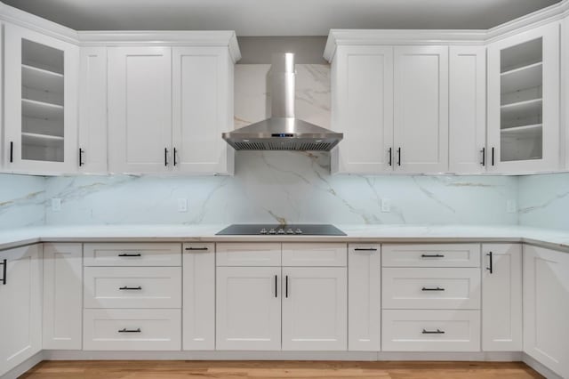 kitchen featuring black electric cooktop, white cabinetry, light countertops, and wall chimney range hood