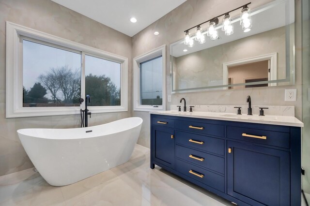 full bathroom featuring a sink, a freestanding tub, marble finish floor, and double vanity