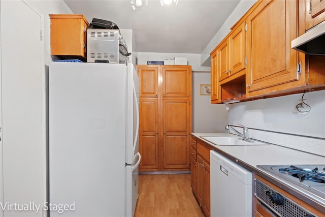 kitchen with white appliances, light wood finished floors, a sink, light countertops, and under cabinet range hood