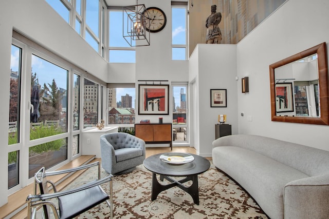 living room with a view of city, a high ceiling, wood finished floors, and a notable chandelier