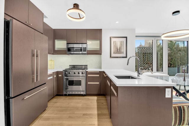 kitchen with light countertops, a sink, a peninsula, and high quality appliances