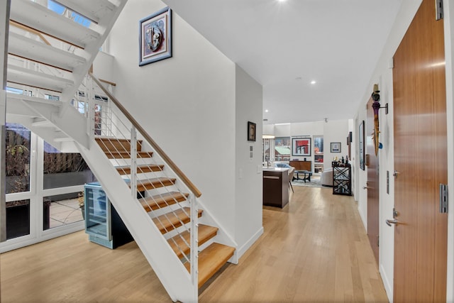 stairs featuring baseboards, wood finished floors, and recessed lighting