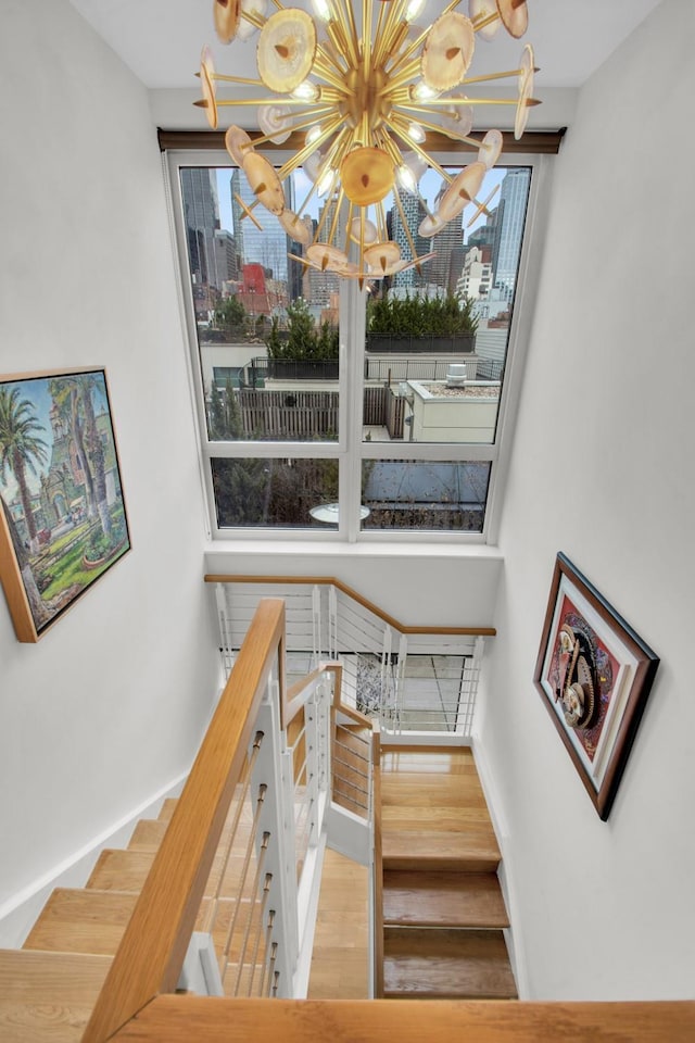 stairs featuring a notable chandelier, baseboards, and wood finished floors