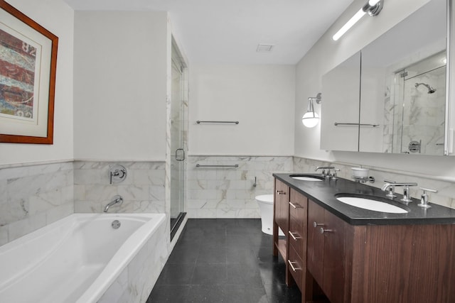 bathroom with tile walls, a sink, toilet, and a shower stall