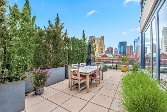 view of patio / terrace with outdoor dining space, a balcony, and a city view