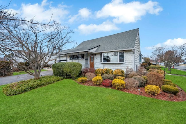 view of front of property with a front lawn, fence, and a shingled roof