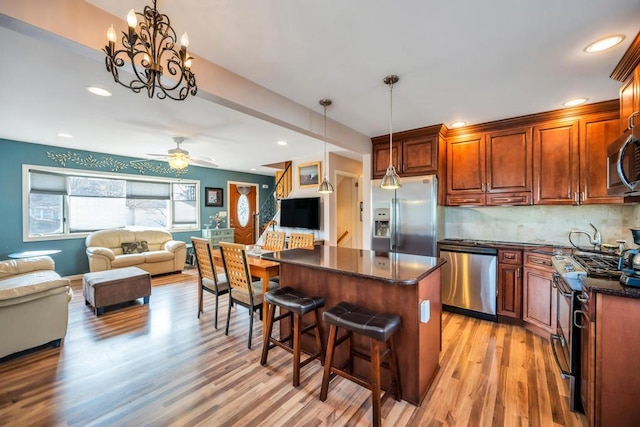 kitchen with a kitchen island, light wood-style floors, appliances with stainless steel finishes, a kitchen breakfast bar, and open floor plan