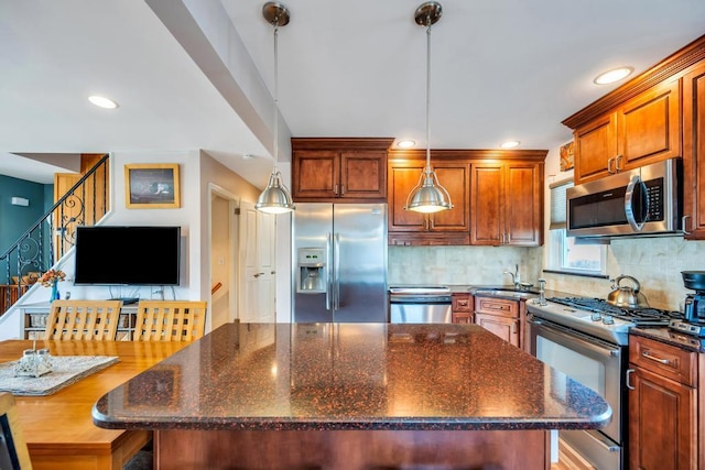 kitchen with a kitchen island, a sink, decorative backsplash, hanging light fixtures, and appliances with stainless steel finishes