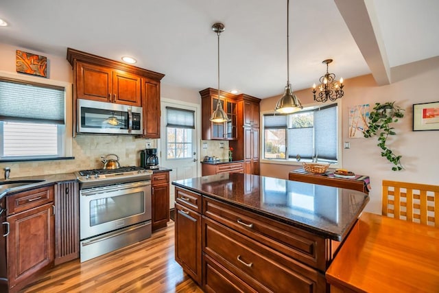 kitchen featuring decorative light fixtures, tasteful backsplash, light wood finished floors, and stainless steel appliances