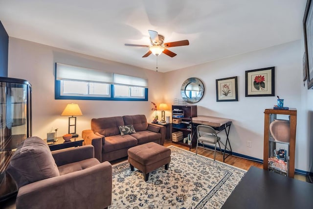 living area featuring ceiling fan, baseboards, and wood finished floors