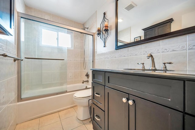 bathroom with visible vents, bath / shower combo with glass door, toilet, tile patterned floors, and tile walls