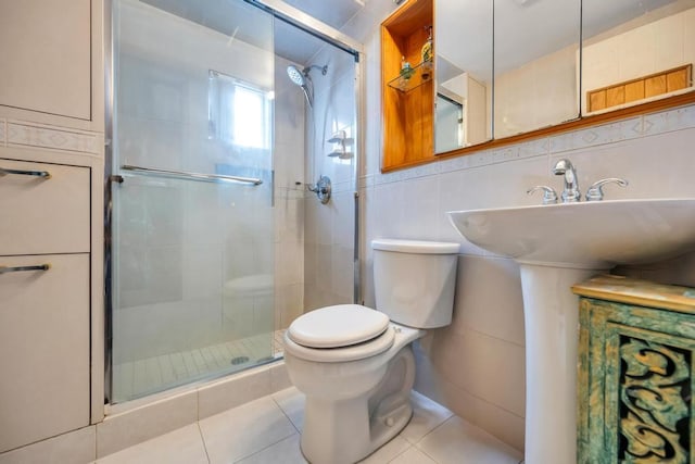 full bath featuring a stall shower, a sink, tile patterned flooring, tile walls, and toilet