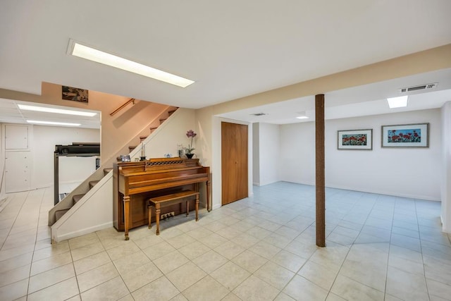 finished basement with visible vents, light tile patterned flooring, and stairs