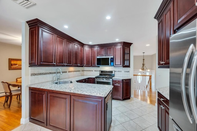 kitchen featuring visible vents, a sink, backsplash, reddish brown cabinets, and appliances with stainless steel finishes