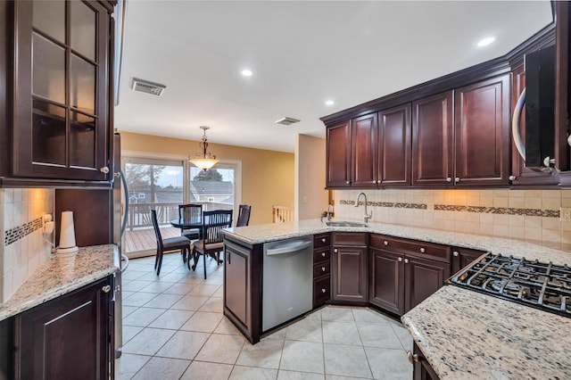 kitchen featuring visible vents, light stone counters, a peninsula, stainless steel dishwasher, and a sink